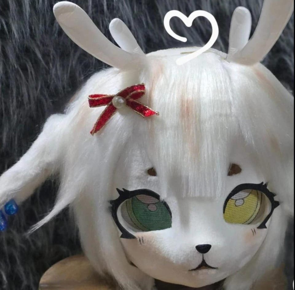 Cabeza estilo kigurumi blanca con peluca, orejas de conejo y ojos grandes de distinto color.