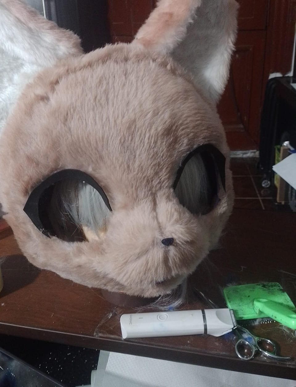 Cabeza de fursuit beige en proceso de armado, sobre un soporte de trabajo.