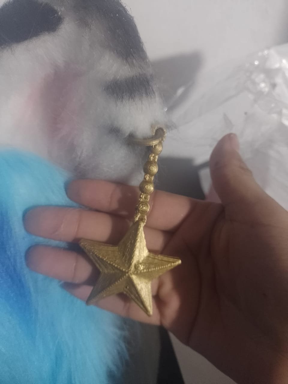Llavero con forma de estrella apoyado sobre el pelaje de una cabeza de fursuit azul y blanco.