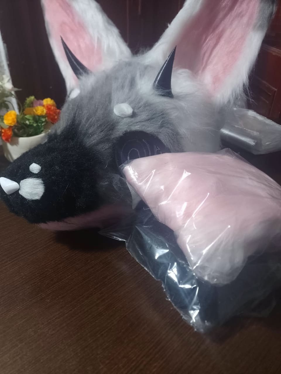 Cabeza de fursuit gris, negra y rosa tipo cachorro, parcialmente embalada.