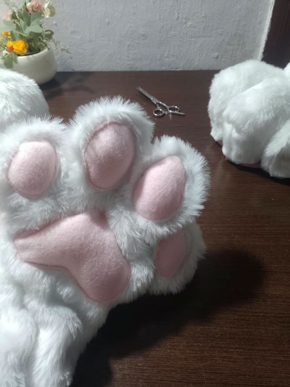 Detalle de pata de fursuit blanca con almohadillas rosas.