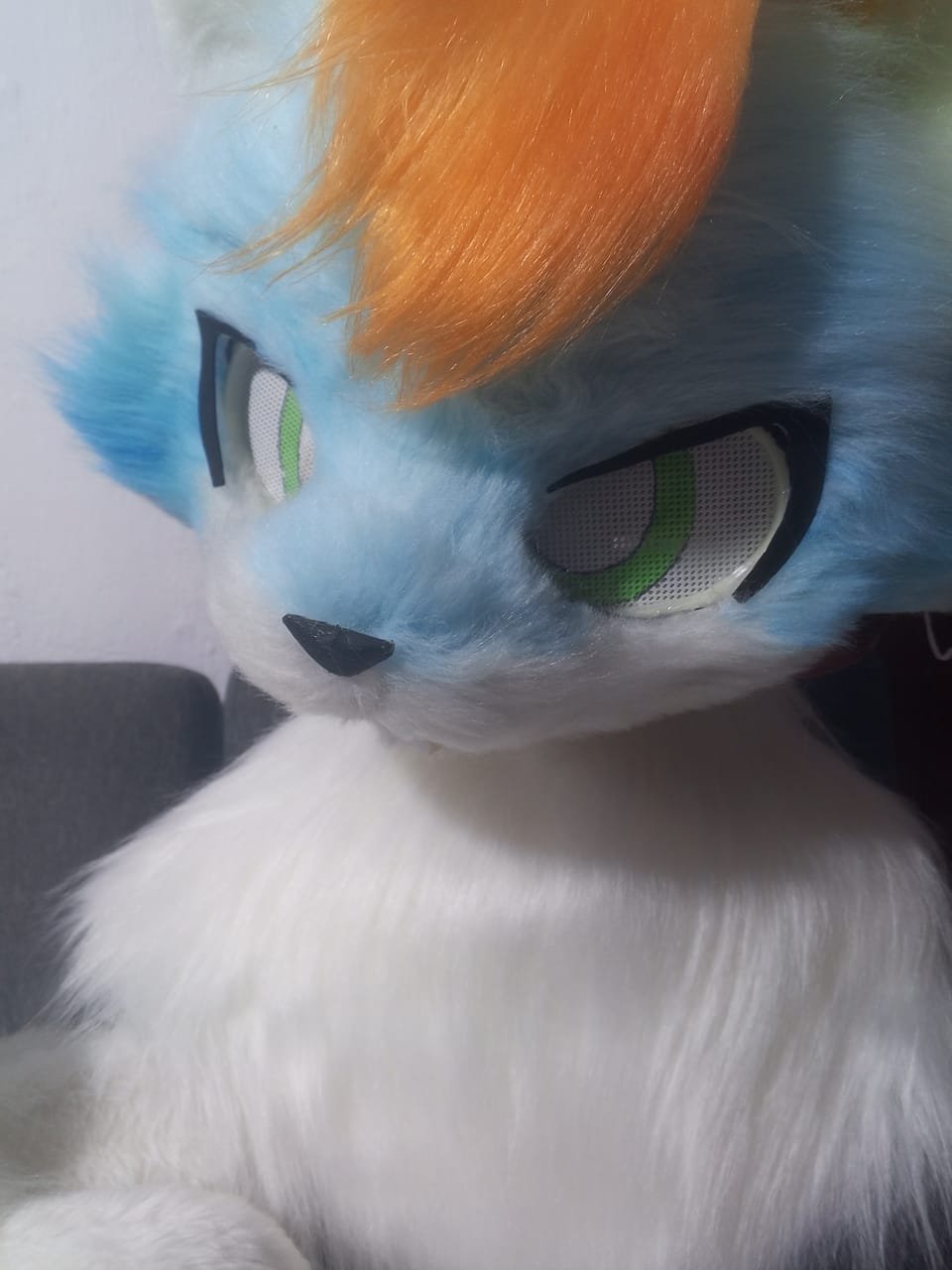 Cabeza de fursuit verde menta tipo zorro con cejas pintadas y ojos rosados.